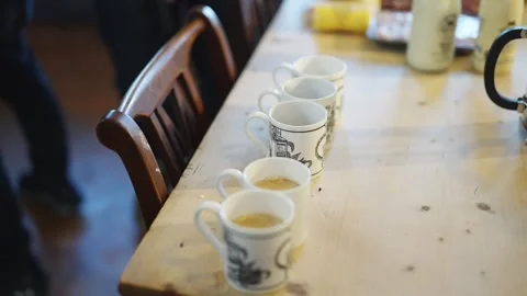 A table with five white cups and a brown chair Stock-Footage 295367150