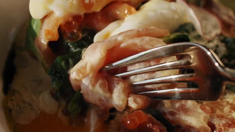 A table fork carves a poached egg and salmon in benedict senwich toast 스톡 동영상 151296963