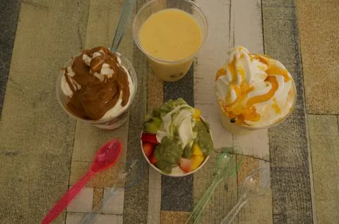 A table with four different types of ice cream and a cup of milk Foto stock