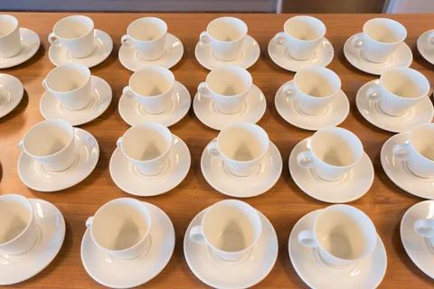 Table full of empty white bistro coffee cups and saucers in order waiting to  Stock Photos