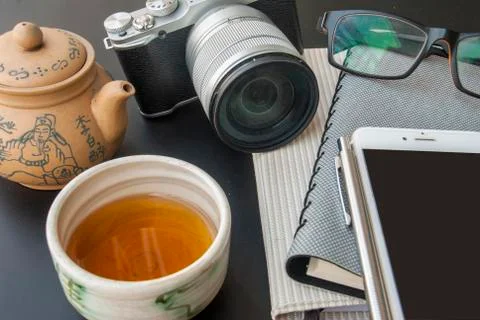 On the table that is full of work equipment, cameras and Chinese tea Stock Photos