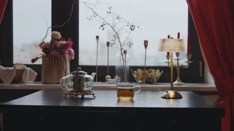 Table with glass teapot and cup by window Stock Footage 315957938