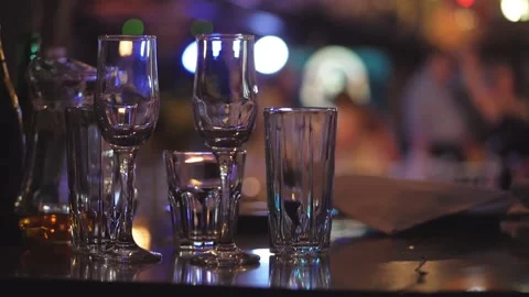 A table with glasses on the background of silhouettes of dancing people, the Stock Footage 156708413