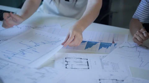 Table with graphs and blueprints apartment in real estate office, women's hands Video stock 65788609