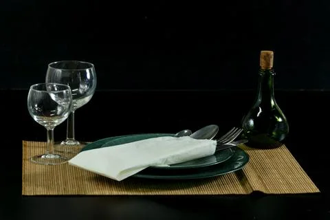 A table with a green plate, fork, knife, and two wine glasses Stock Photos