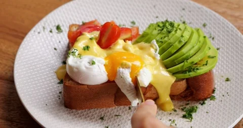 Table knife presses the poached egg and it bursts, liquid yolk inside Stock Footage 240302237