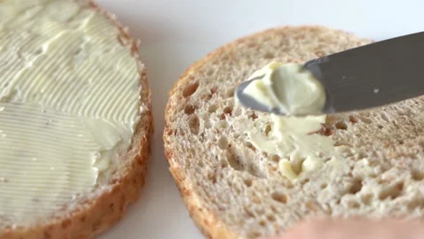 A table knife spreading soft butter over the surface of a grainy, porous slice Stock Footage 160906775