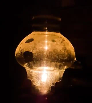 Table lamp burning at night time on the table and dark background. Stock Photos