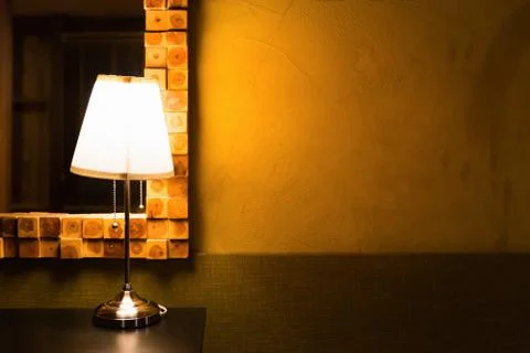 Table lamp shining warm light on grunge wall Stock Photos