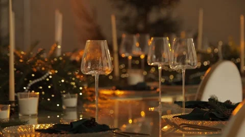 A table with large glasses and garlands, illuminated by a yellow light. Stock Footage 324850648