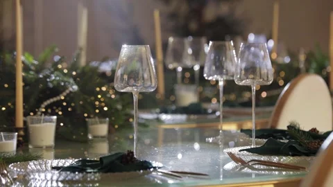 A table with large glasses and garlands, illuminated by a white light. The wine  Stock Footage 324850663