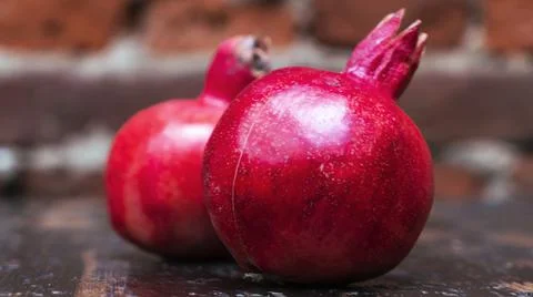 On the table lay two red pomegranate. Two ripe garnet on the table on red bri Foto stock
