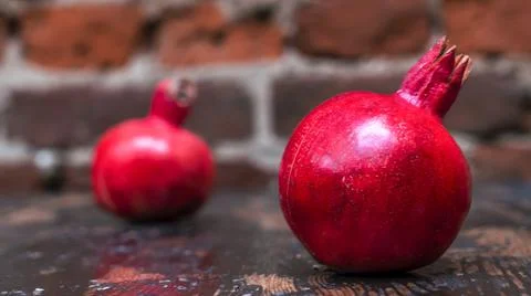 On the table lay two red pomegranate. Two ripe garnet on the table on red bri Foto stock