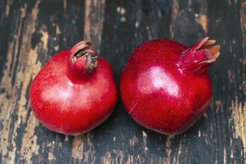 On the table lay two red pomegranate. Two ripe garnet on the wooden table. Ha Stock Photos