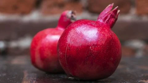 On the table lay two red pomegranate. Two ripe garnet on the table on red bri Foto stock