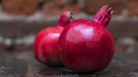 On the table lay two red pomegranate. Two ripe garnet on the table on red bri Foto stock