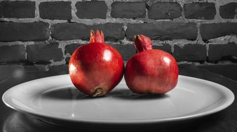 On the table lay two red pomegranate. Two ripe garnet on the table on black a 库存照片