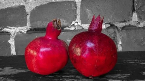 On the table lay two red pomegranate. Two ripe garnet on the table on black a 库存照片