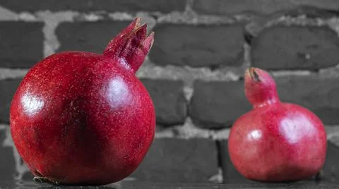 On the table lay two red pomegranate. Two ripe garnet on the table on black a 库存照片