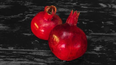 On the table lay two red pomegranate. Two ripe garnet on the table on black a Stock Photos
