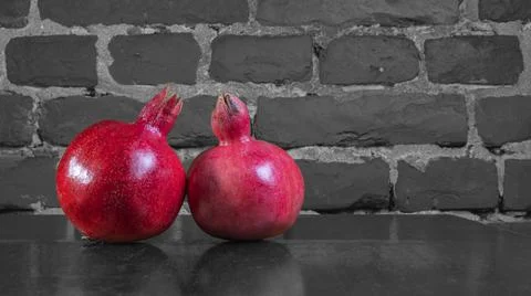On the table lay two red pomegranate. Two ripe garnet on the table on black a Foto stock
