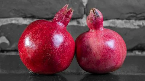 On the table lay two red pomegranate. Two ripe garnet on the table on black a Foto stock