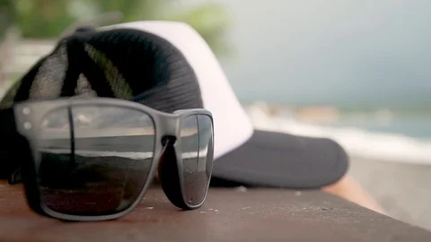 On the table lies a cap and glasses in which the waves of the ocean are Stock Footage 126974431