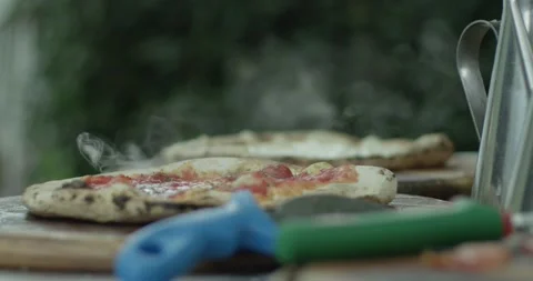 On the table lies a hot pizza from which steam comes. Slow motion close up. Stock Footage 130599756