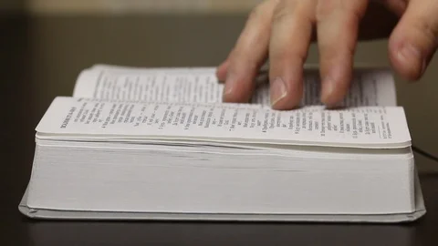 On the table lies an open Bible. A man slowly leafing through pages in search Stock Footage 126544029