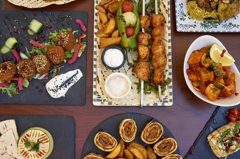 A table with many different types of food, including a plate of hummus Stock Photos