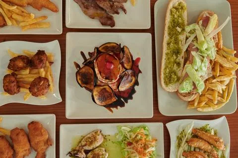 A table with many different types of food, including sandwiches, fries, and.. Stock Photos