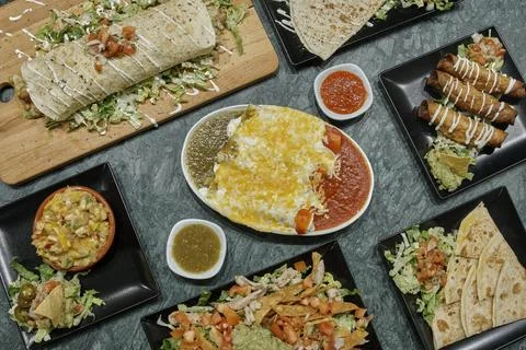 A table with many different types of food, including burritos, enchiladas Stock Photos
