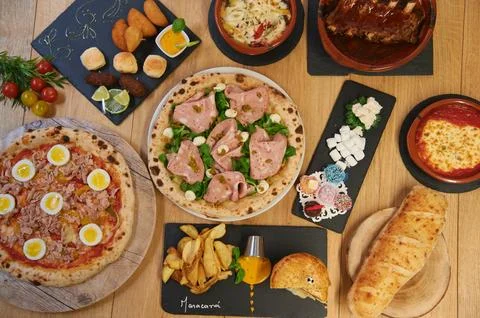 A table with many different types of food, including pizza, bread Stock Photos