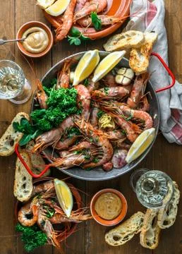 Table with many plates with shrimps, bread, lemons and wine, top view Stock Photos