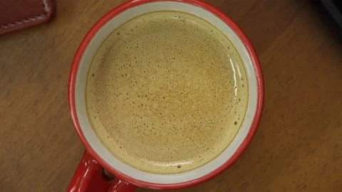 On the table next to the phone and keyboard is a red cup of coffee Stock Footage 100114034