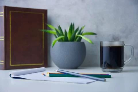 Table with notepad, coloured crayons, with coffee, flower and an old photo album Stock Photos