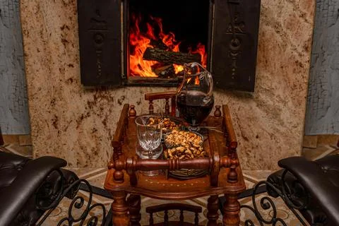 A table with nuts and drinks against the background of an old fireplace. Foto stock