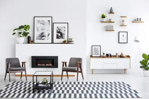 Table on patterned carpet in white living room interior with grey armchairs a Stock Photos