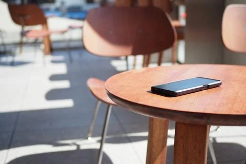 Table with phone at cafe in the daylight. lost smart phone on a table Stock Photos