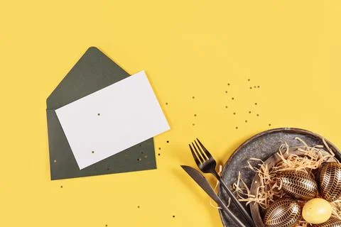 Table place setting with empty greeting or invitation card and Easter eggs Stock Photos