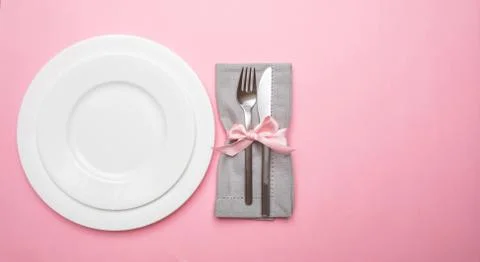 Table place setting in pink. Gray linen napkin with ribbon and white plates o Foto stock
