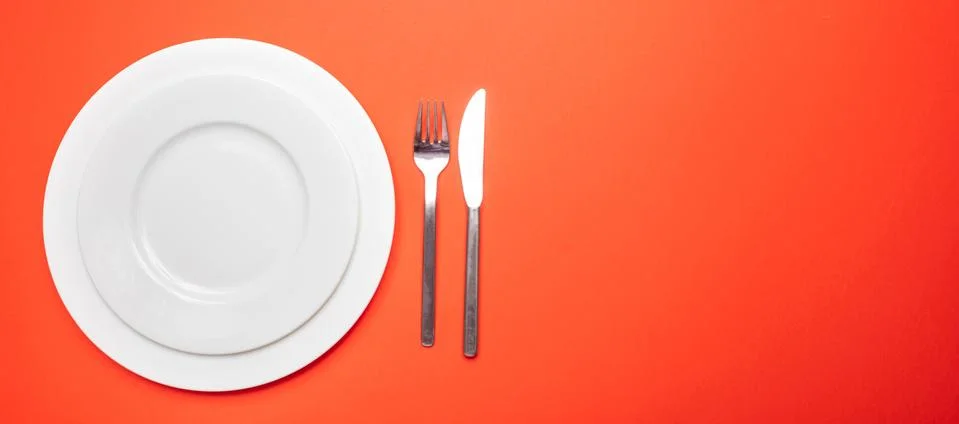 Table place setting on red. Set of empty white plates and cutlery on red, ora Stock Photos