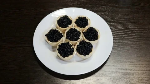 On the table is a plate of canapes of black caviar Stock Footage 73067768