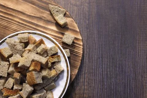 On the table is a plate with cubes of black bread crackers. Foto stock