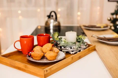 On the table is a plate of muffins, two red cups and a candle. New Year Stock Photos