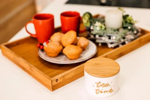 On the table is a plate of muffins, two red cups and a candle. New Year Stock Photos