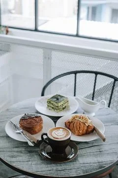 A table with plates of bakery and cups of coffee on it Stock Photos