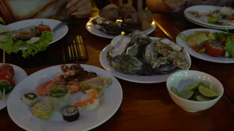 Table with plates of seafood. Women's hands take the oyster Stock Footage 91484044