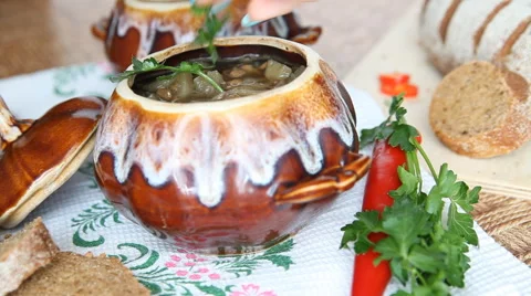 On the table is a pot of soup. The dish is decorated with a sprig of greenery. Stock Footage 61943503