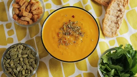 On the table is pumpkin cream soup, served with croutons, pumpkin seeds, and Stock Footage 316894622